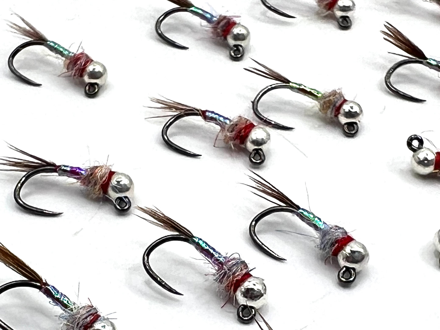 Assorted rainbow fishing jigs with silver heads, iridescent bodies, and feather hackles