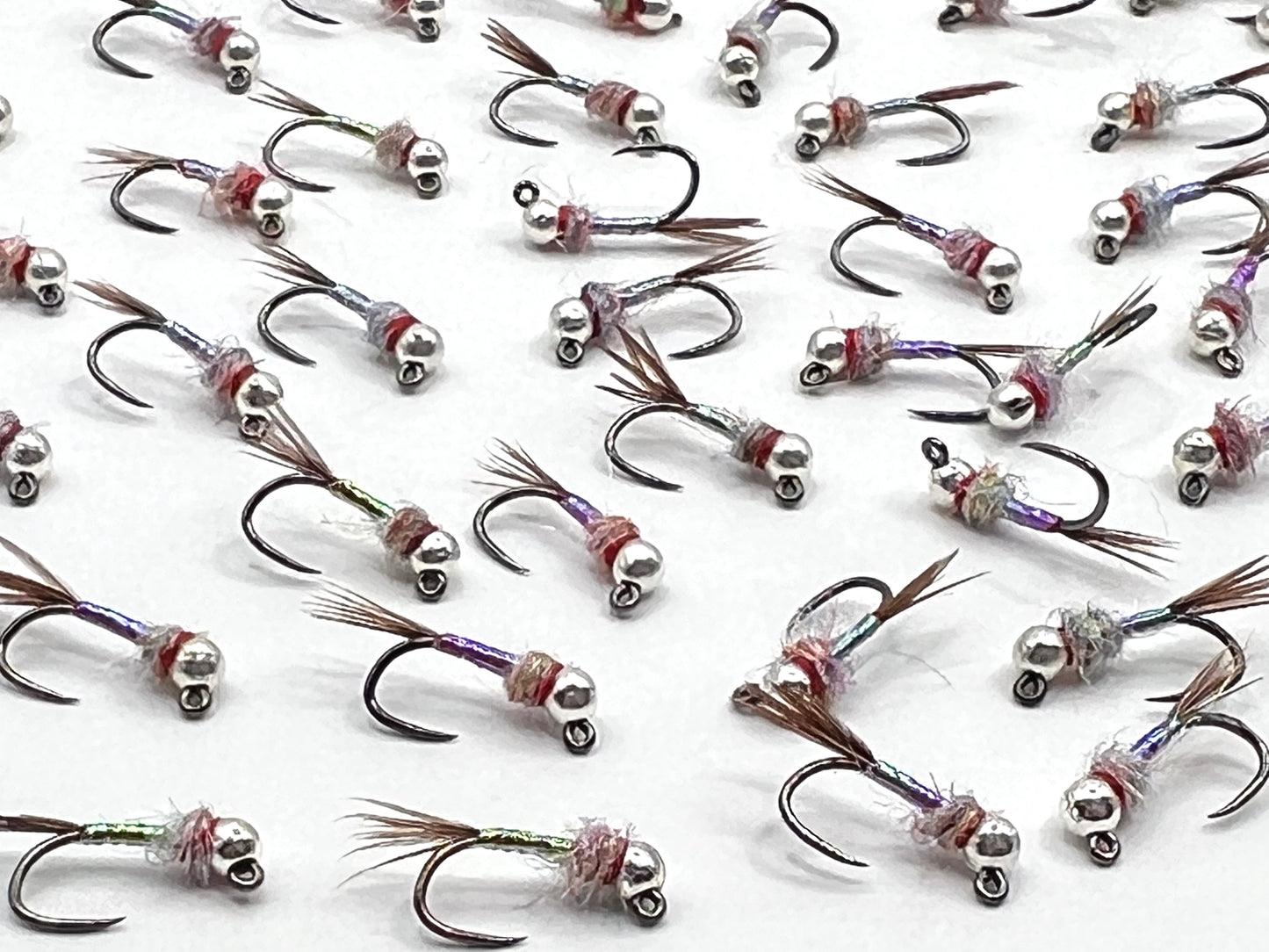 Multiple Rainbow Warriors jigs with brown feather tails, rainbow sparkle bodies and hooks