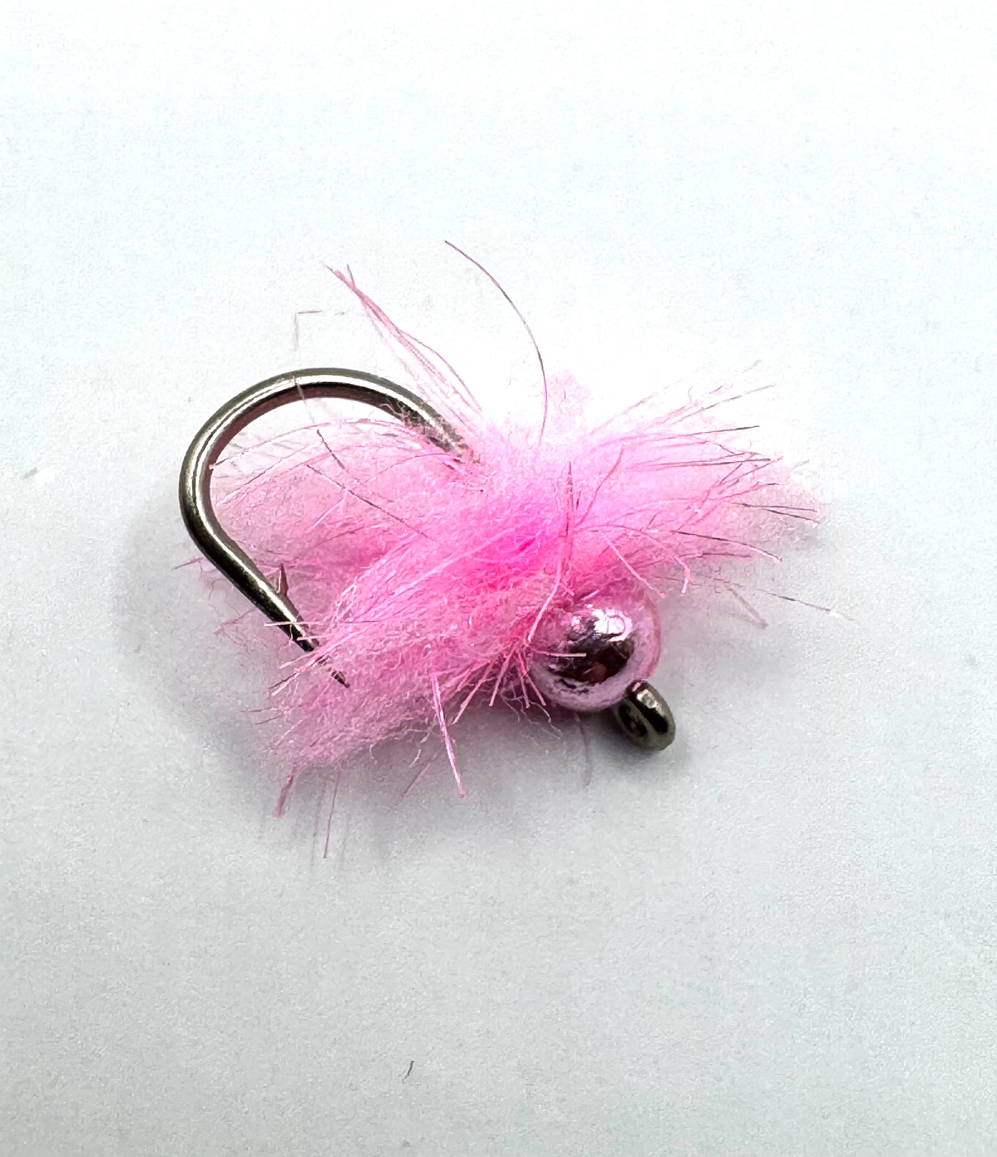 Pink fuzzy fly fishing jig with two dark bead eyes on a black hook