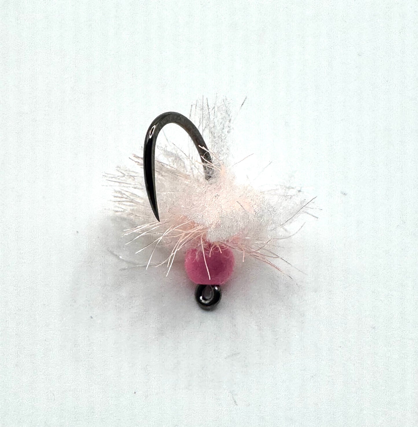 Pink bead fly fishing egg lure on black hook with white and pale fibers