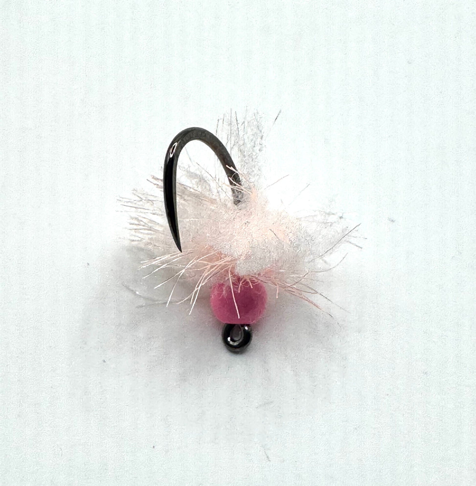 Pink bead fly fishing egg lure on black hook with white and pale fibers