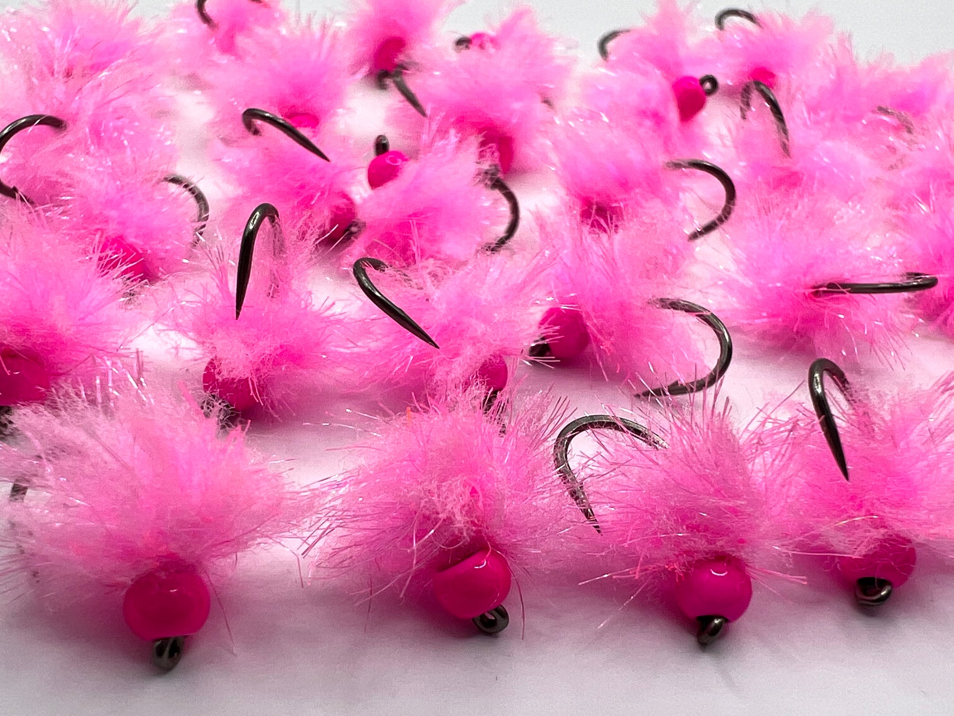 Pink tungsten egg fly close-up with fuzzy pink fibers and black hook points